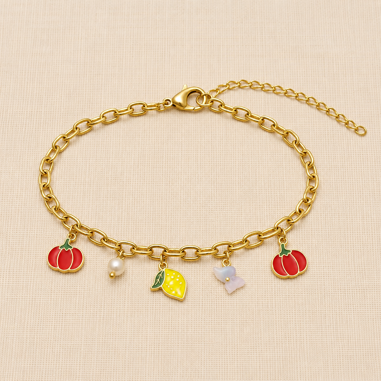 Anti Tarnish charm bracelet featuring pumpkin, lemon, butterfly, and pearl charms worn on a woman's wrist against a cream beige background.