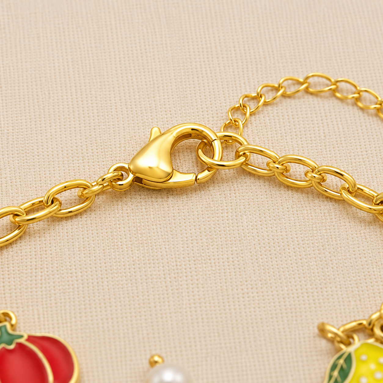 Anti Tarnish charm bracelet featuring pumpkin, lemon, butterfly, and pearl charms worn on a woman's wrist against a cream beige background.